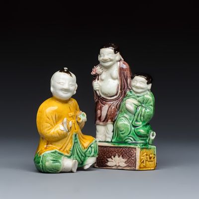 A Chinese famille verte sancai biscuit model of a seated boy and a 'He He Er Xian' group, Kangxi
