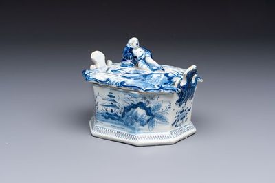 A blue and white Dutch Delft chinoiserie butter tub with a reclining figure finial, 18th C.