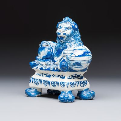 A blue and white Dutch Delft model of a recumbent lion holding a globe, 18th C.
