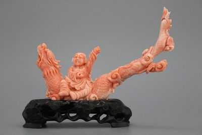 A carved Chinese red coral group of a boy on a dragon, 19/20th C.