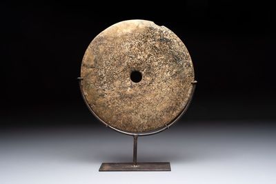 A Chinese archaic calcified jade 'bi' disc on an iron stand, possibly Zhou