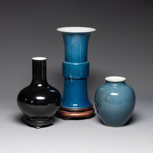 A Chinese black-glazed bottle vase, a blue-glazed jar and a powder-blue 'gu' vase on a wooden stand, Qianlong mark, 19/20th C. — photo 1