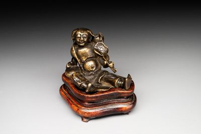 A Chinese bronze paperweight in the form of 'Shi De 拾得' on wooden stand, 16th C.