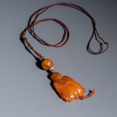 A Chinese carved amber pendant of a Bodhisattva, Qing