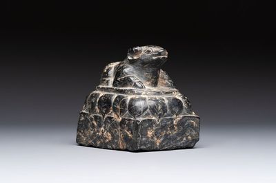 A Chinese carved black stone paper weight in the shape of a reclining buffalo on a lotus throne, Northern and Southern dynasties