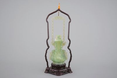 A Chinese carved green jadeite vase and cover on elaborate wooden stand, 19/20th C.
