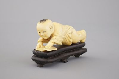 A Chinese carved ivory figure of a boy reading a book, 19/20th C.