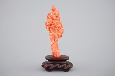 A Chinese carved red coral figure on a wooden stand, 19/20th C.