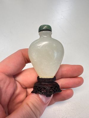 A Chinese carved white jade 'Geese' snuff bottle on a wooden stand — photo 1