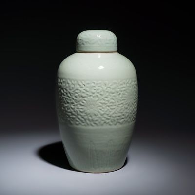 A Chinese celadon-glazed covered vase with floral relief design, Qianlong mark and of the period