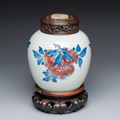 A Chinese copper-red, blue and white 'Fruits' jar with a jade-inset wooden cover and a stand, Kangxi