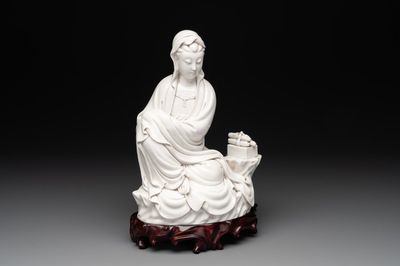 A Chinese Dehua blanc de Chine figure of a seated Guanyin on wooden stand, 19/20th C.