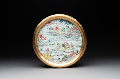 A Chinese famille rose plate with figures in a river landscape in gilt wooden frame, Yongzheng