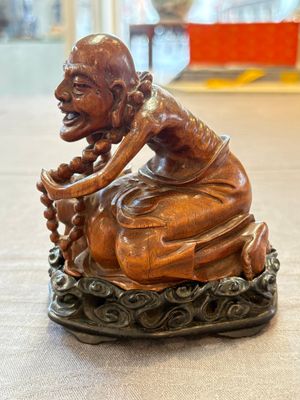 A Chinese fine huanghuali sculpture of a Luohan on a zitan stand, Qianlong mark, 19/20th C. — photo 1