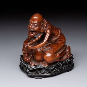 A Chinese fine huanghuali sculpture of a Luohan on a zitan stand, Qianlong mark, 19/20th C. — photo 1