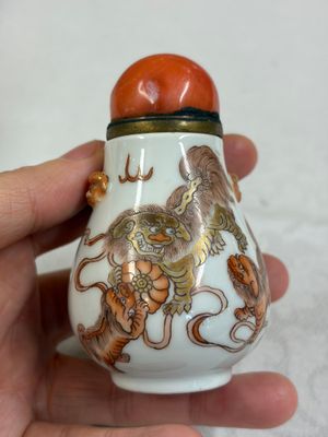 A Chinese gilt iron-red-decorated 'Buddhist Lions' snuff bottle with a red coral stopper — foto 1