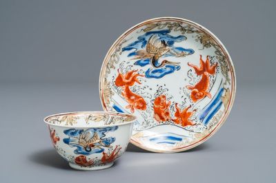 A Chinese iron red, grisaille, gilt and overglaze blue 'carps and crane' cup and saucer, Yongzheng