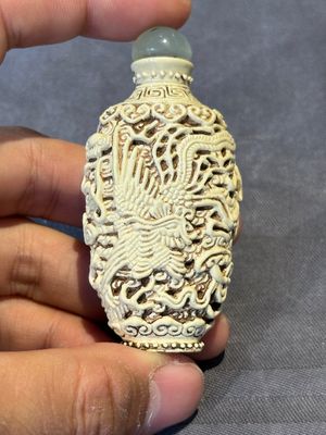 A Chinese moulded cream-glazed 'dragon and phoenix' snuff bottle, Jiaqing mark, 19th C. — foto 1