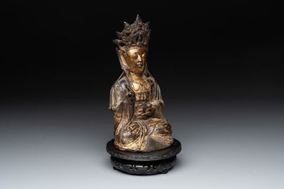 A Chinese parcel-gilt bronze Guanyin and wooden stand, Ming