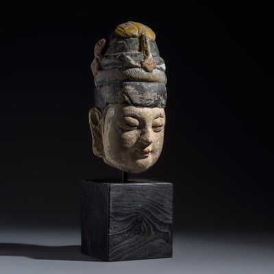A Chinese polychromed carved stone head on a stand, Ming