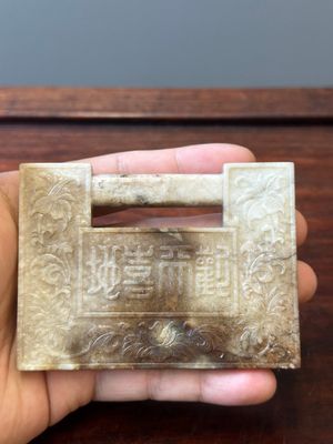 A Chinese white and russet jade lock-shaped plaque with inscription 'Huan Tian Xi Di 歡天喜地', Qing — 照片 1