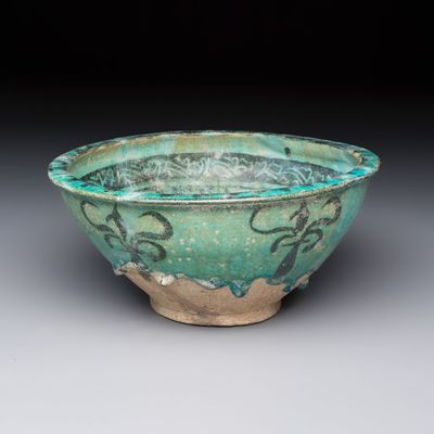 A Kashan black and turquoise pottery bowl with a calligraphic border, Persia, 12/13th C.