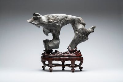 A large Chinese Lingbi stone scholar's rock on wooden stand, 19/20th C.