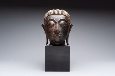 A large Thai bronze Shakyamuni Buddha head on wooden stand, Chieng Sen period, 16th C.