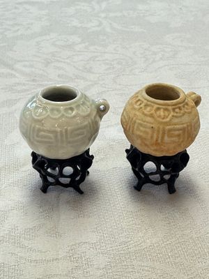 A pair of Chinese bird feeders with moulded design, one unglazed, on later wooden stands, Song — photo 1
