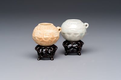 A pair of Chinese bird feeders with moulded design, one unglazed, on later wooden stands, Song