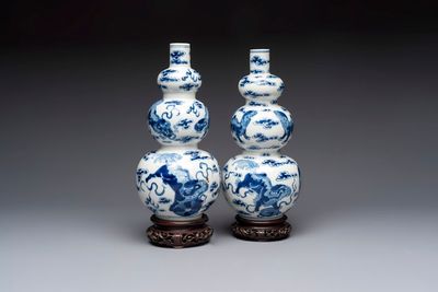 A pair of Chinese blue and white 'Buddhist Lions' triple gourd vases on reticulated wooden stands, 19th C.