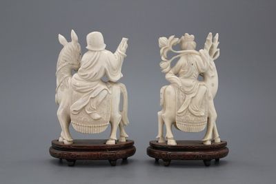 A pair of Chinese carved ivory figures on a wooden base, early 20th C.