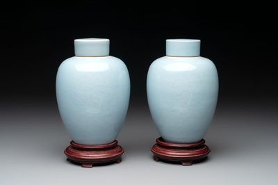 A pair of Chinese claire-de-lune jars and covers on wooden stands, Kangxi mark, 19th C.