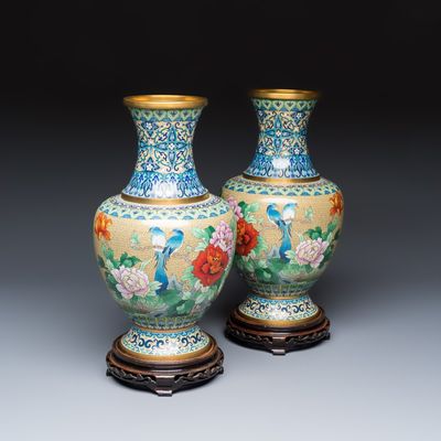 A pair of Chinese cloisonné vases with birds among flowering branches on wooden stands, 20th C.
