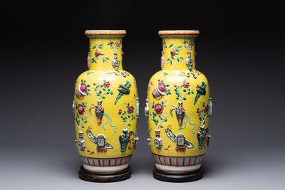 A pair of Chinese famille rose yellow-ground relief-decorated vases with wooden stands, 19th C.