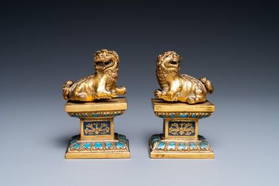 A pair of Chinese gilt copper alloy Buddhist lions on champlevé enamel bases, 19th C.