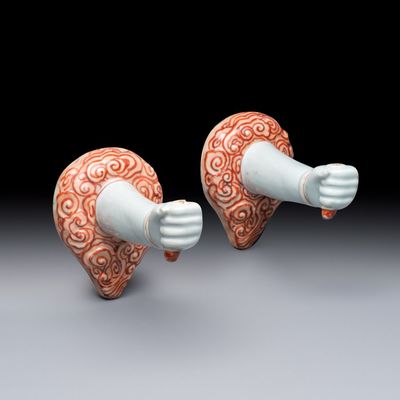 A pair of Chinese iron-red and gilt-decorated wall sconces in the shape of an arm, 18/19th C.