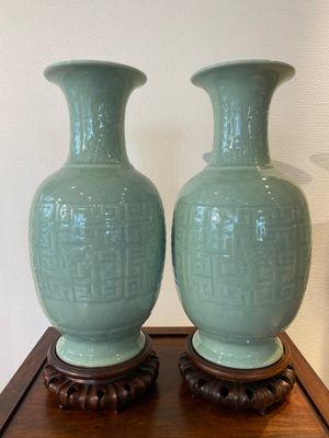 A pair of Chinese monochrome celadon-glazed vases with underglaze design on wooden stands, Qianlong mark, 18/19th C. — 照片 1