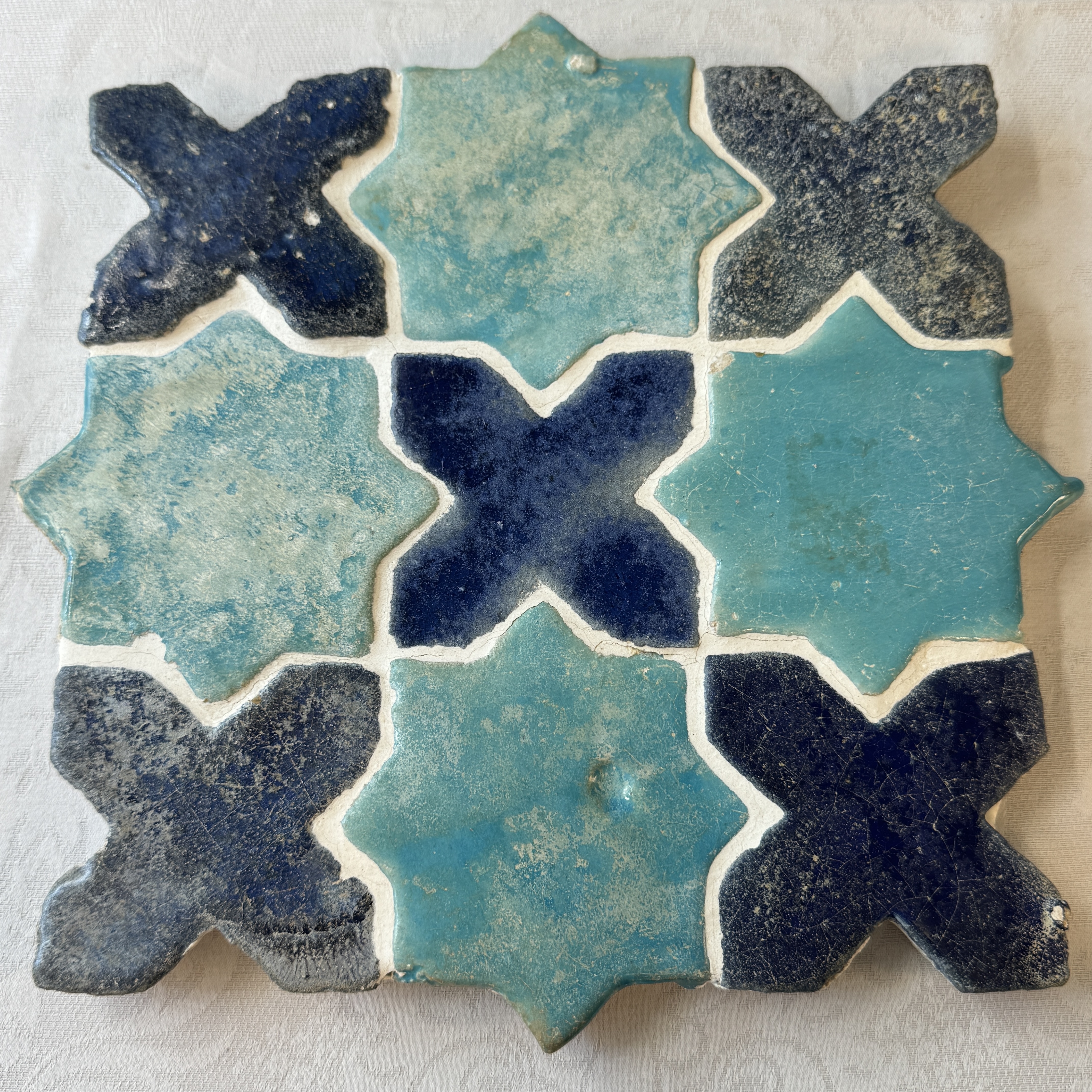 A panel of nine Kashan turquoise- and blue-glazed star and cross tiles — photo 1