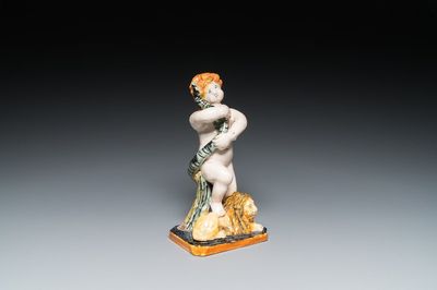 A polychrome Brussels faience sculpture of a putto with a snake standing on a lion, late 18th C.