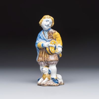 A polychrome Dutch Delft figure of a hurdy-gurdy player with a dog, 18th C.