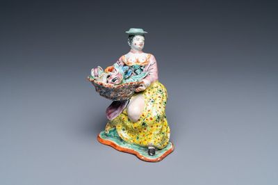 A polychrome Dutch Delft petit feu figure of a bare-breasted flower seller, 18th C.