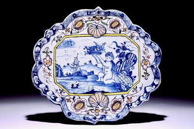A polychrome Dutch Delft plaque with a putto holding a fruit basket, 18th C.