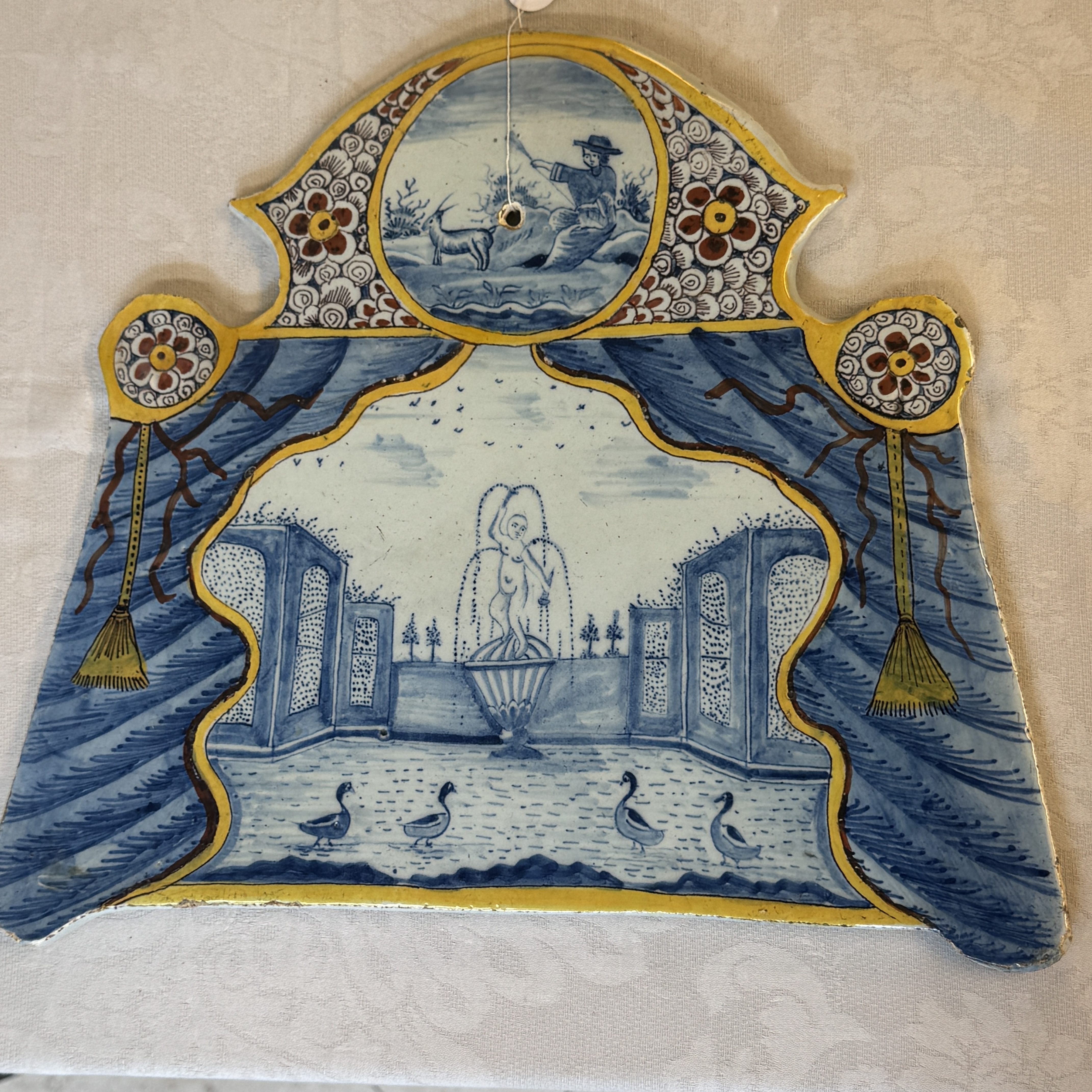 A polychrome Dutch Delft trompe-l'oeil plaque with a fountain garden in a theatrical curtain frame — foto 1