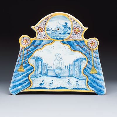 A polychrome Dutch Delft trompe-l'oeil plaque with a fountain garden in a theatrical curtain frame, 18th C.