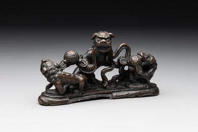 A rare Chinese bronze 'three dancing lions' paperweight or brush rest, Ming