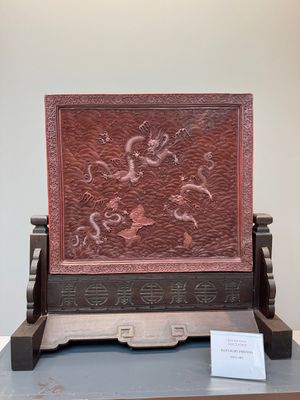 A rectangular Chinese carved red lacquer 'dragon' table screen, later wooden stand, Qianlong — photo 1