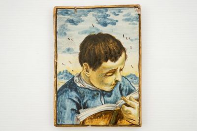 A small Italian Castelli plaque with a reading boy, 17/18th C.