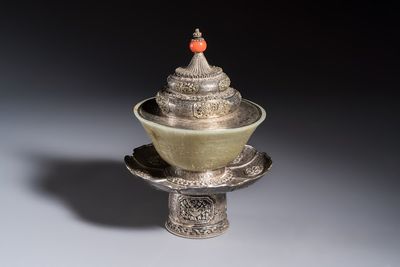 A Tibetan ritual jade bowl with a red coral-mounted silver cover and a stand, 19th C.