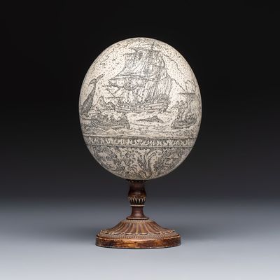 An engraved ostrich egg with a maritime scene on a wooden stand, 20th C.